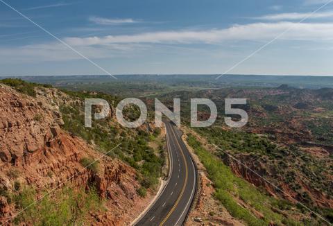A wide Texas landscape with a river, hills, and trees at sunset